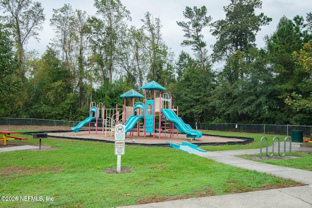 community playground featuring a yard and fence