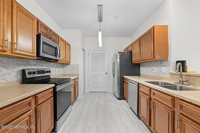 kitchen with pendant lighting, stainless steel appliances, light countertops, brown cabinetry, and a sink