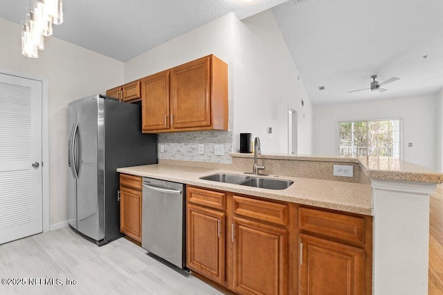 kitchen with brown cabinets, decorative light fixtures, stainless steel appliances, light countertops, and a sink