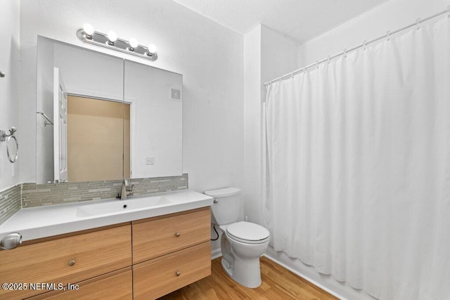 bathroom with toilet, tasteful backsplash, wood finished floors, and vanity