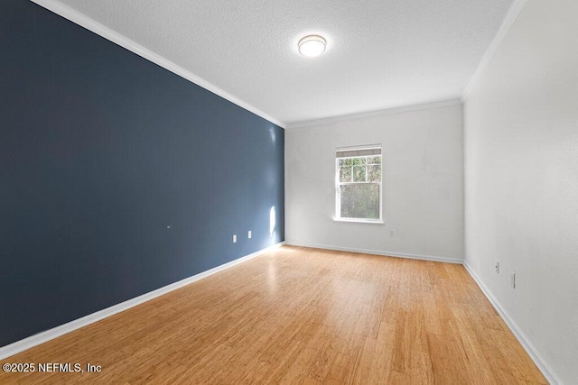 empty room featuring a textured ceiling, light wood finished floors, ornamental molding, and baseboards