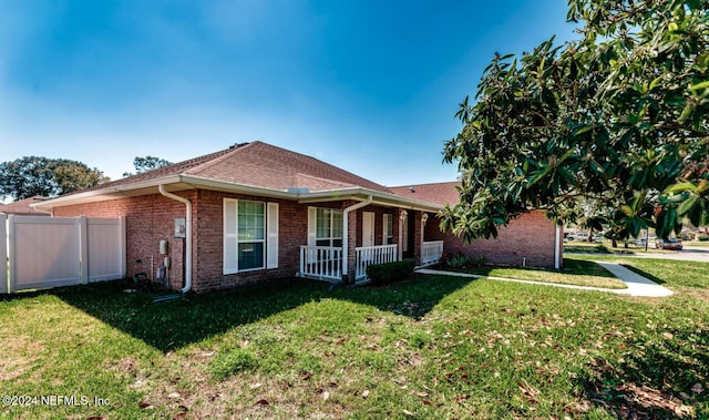 ranch-style home featuring covered porch and a front lawn