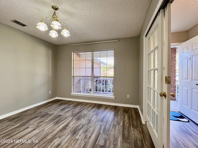 unfurnished room featuring dark hardwood / wood-style flooring, a chandelier, and a textured ceiling