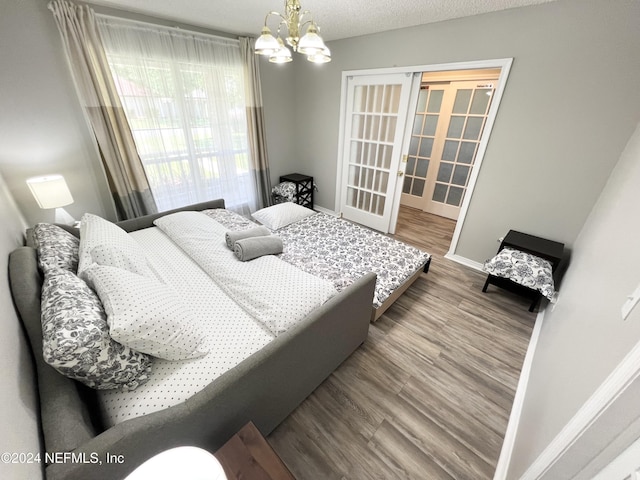 bedroom with hardwood / wood-style flooring, a chandelier, french doors, and a textured ceiling