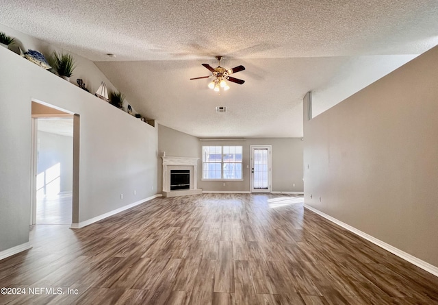 unfurnished living room featuring ceiling fan, lofted ceiling, a textured ceiling, and dark hardwood / wood-style flooring