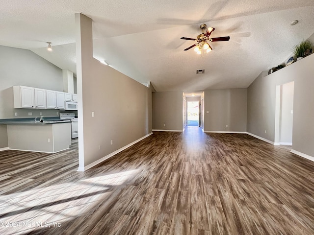 unfurnished living room featuring lofted ceiling, dark wood-type flooring, a textured ceiling, and ceiling fan