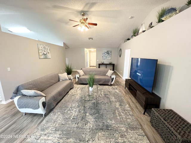 living room featuring ceiling fan, lofted ceiling, a textured ceiling, and light hardwood / wood-style floors