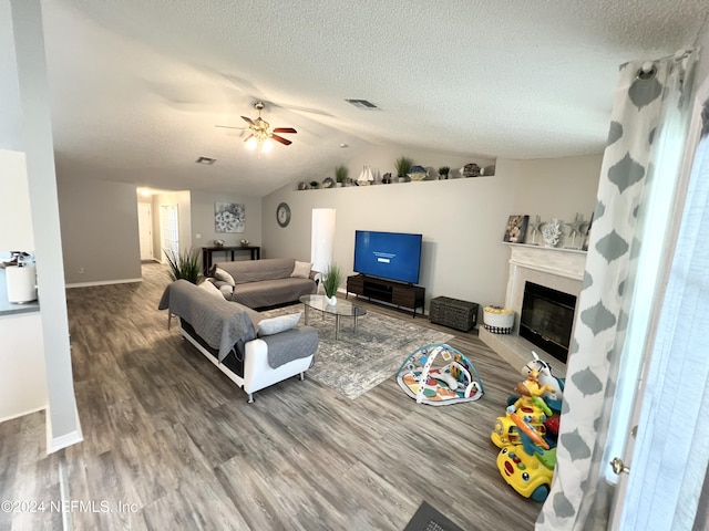 living room with ceiling fan, lofted ceiling, wood-type flooring, and a textured ceiling