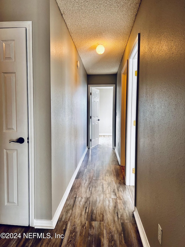 hall with hardwood / wood-style floors and a textured ceiling