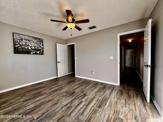 unfurnished bedroom featuring ceiling fan, dark wood-type flooring, and a textured ceiling