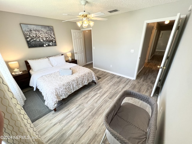 bedroom with hardwood / wood-style flooring, ceiling fan, and a textured ceiling