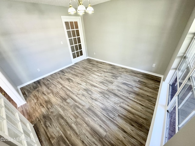 unfurnished dining area featuring hardwood / wood-style floors, a textured ceiling, and an inviting chandelier