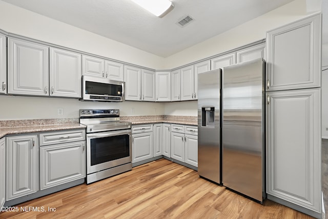 kitchen with appliances with stainless steel finishes and light hardwood / wood-style floors