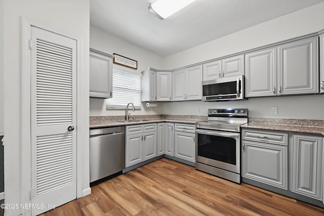 kitchen featuring gray cabinetry, sink, stainless steel appliances, and light wood-type flooring