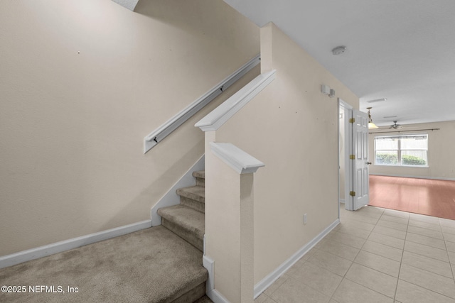 stairway featuring ceiling fan and tile patterned flooring