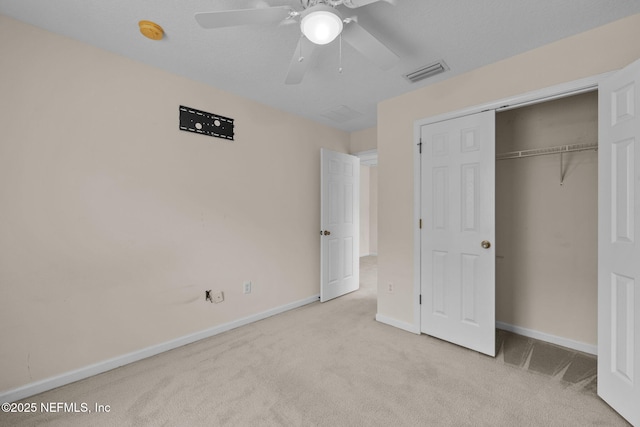 unfurnished bedroom featuring ceiling fan, light colored carpet, a closet, and a textured ceiling