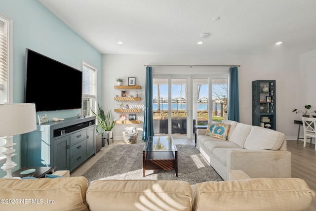 living area with light wood-type flooring, baseboards, and a healthy amount of sunlight