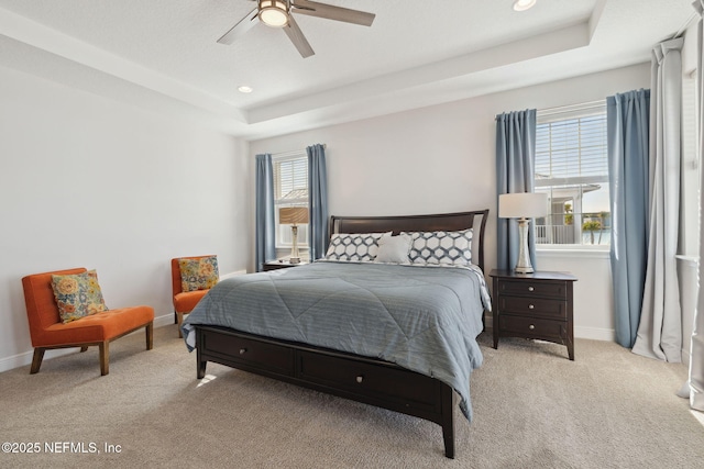 bedroom with recessed lighting, a tray ceiling, light carpet, and baseboards