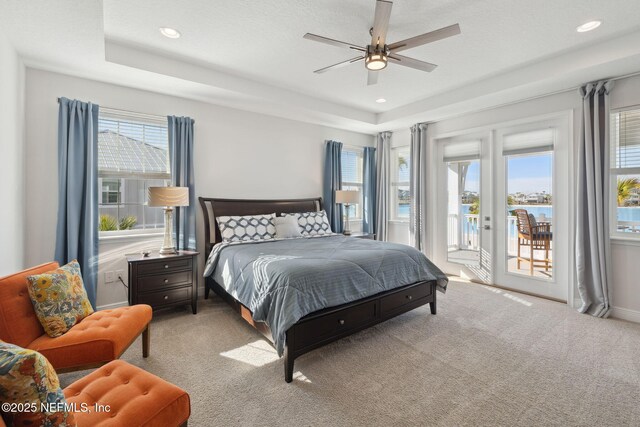 carpeted bedroom featuring ceiling fan, a tray ceiling, recessed lighting, baseboards, and access to exterior