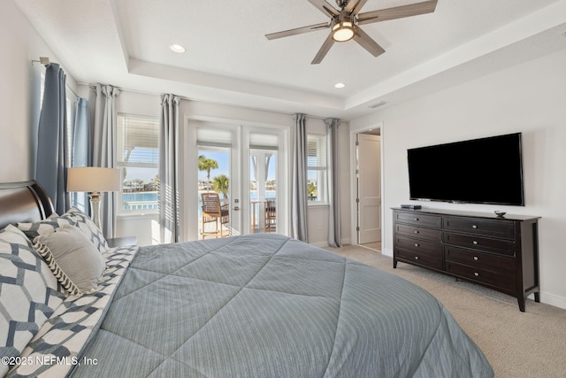 bedroom featuring baseboards, light colored carpet, a tray ceiling, french doors, and access to outside