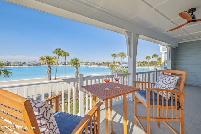 balcony featuring a beach view, ceiling fan, and a water view