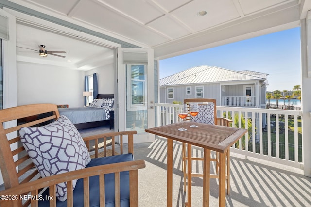 balcony with a water view and a ceiling fan