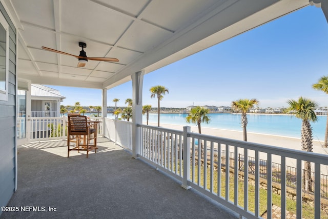 balcony with a water view, ceiling fan, and a beach view