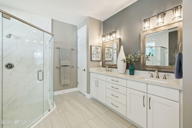 bathroom with double vanity, a stall shower, baseboards, and a sink