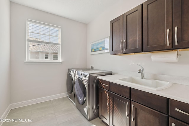 washroom featuring washing machine and clothes dryer, cabinet space, baseboards, and a sink