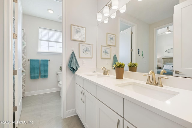 ensuite bathroom featuring double vanity, toilet, ensuite bathroom, and a sink