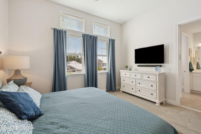 bedroom featuring connected bathroom, baseboards, and light colored carpet