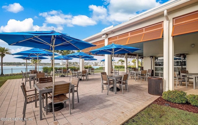 view of patio with a water view and fence