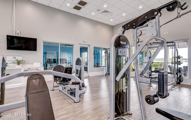 gym with recessed lighting, wood finished floors, baseboards, and a towering ceiling