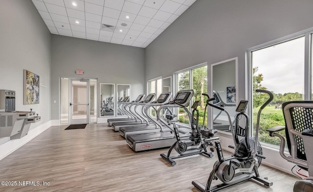 workout area featuring visible vents, a drop ceiling, wood finished floors, baseboards, and a towering ceiling