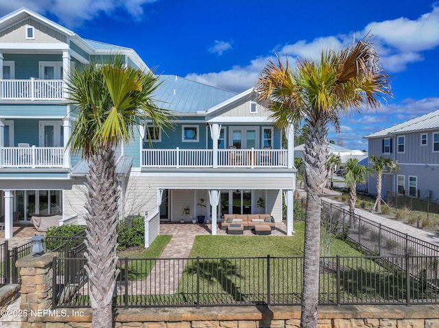 beach home featuring a front lawn, a patio, a fenced backyard, board and batten siding, and outdoor lounge area