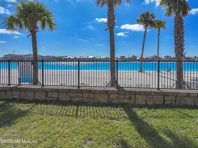 view of swimming pool featuring a water view, a yard, and fence