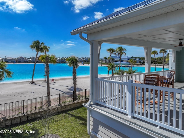 exterior space featuring a beach view, a water view, and fence