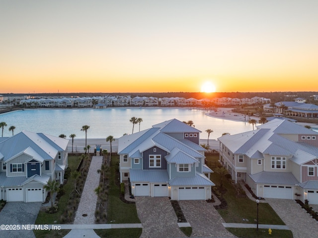 aerial view at dusk featuring a residential view and a water view