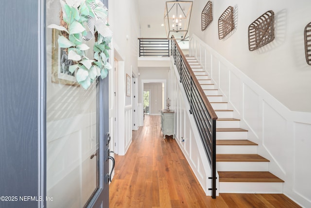 entrance foyer with hardwood / wood-style floors, a notable chandelier, and a high ceiling