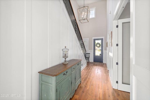 entryway with a towering ceiling, plenty of natural light, dark hardwood / wood-style floors, and a chandelier