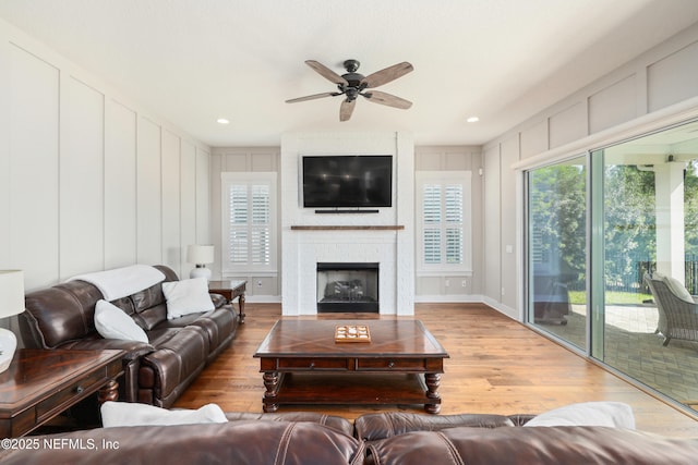 living room featuring a brick fireplace, hardwood / wood-style floors, and ceiling fan