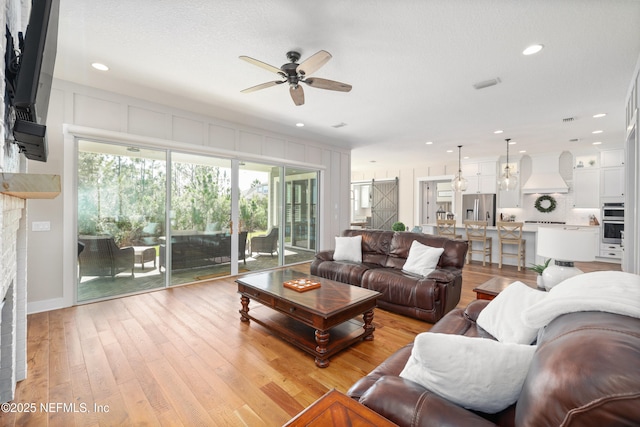 living room with ceiling fan and light wood-type flooring