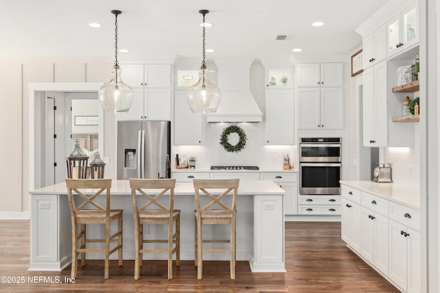 kitchen featuring a kitchen island, premium range hood, white cabinets, and appliances with stainless steel finishes