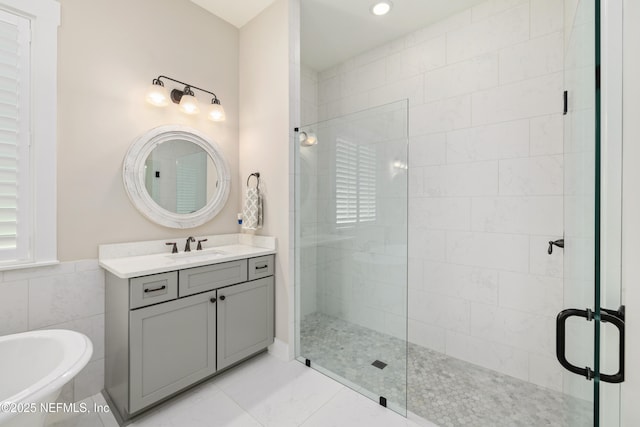 bathroom with shower with separate bathtub, tile walls, and vanity