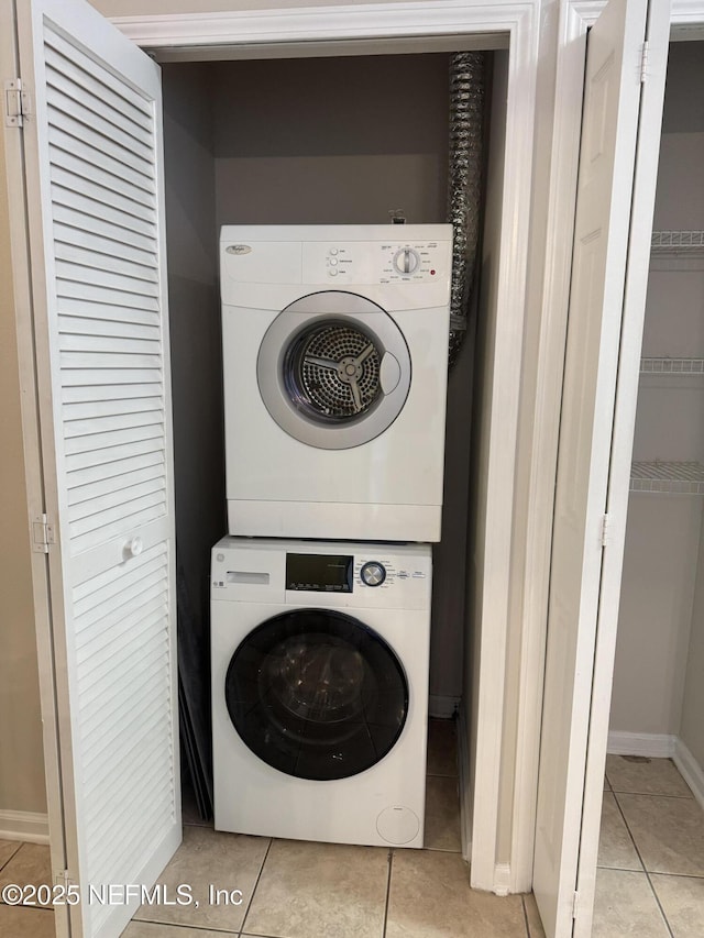 laundry room featuring stacked washer and dryer and light tile patterned floors