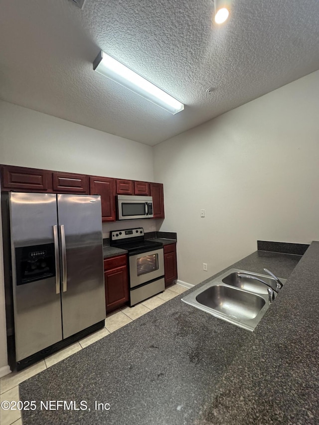 kitchen featuring stainless steel appliances, sink, a textured ceiling, and light tile patterned floors