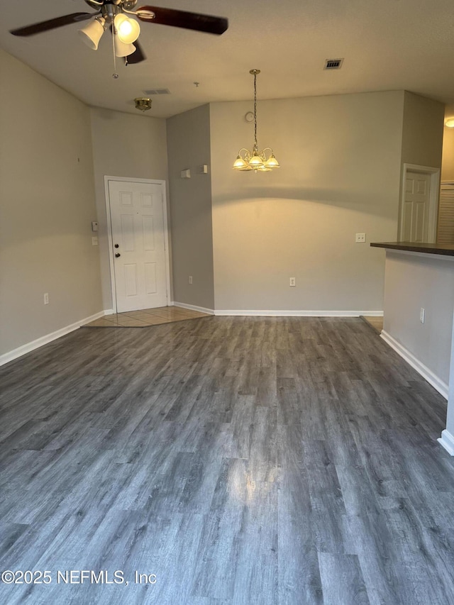 unfurnished living room featuring dark wood-type flooring and ceiling fan with notable chandelier