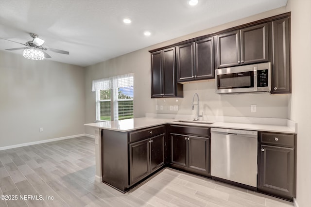 kitchen featuring appliances with stainless steel finishes, kitchen peninsula, sink, and dark brown cabinets