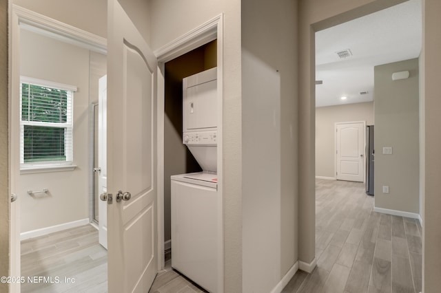 clothes washing area featuring stacked washer and dryer and light hardwood / wood-style floors