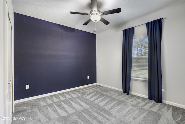 carpeted empty room featuring ceiling fan and a textured ceiling